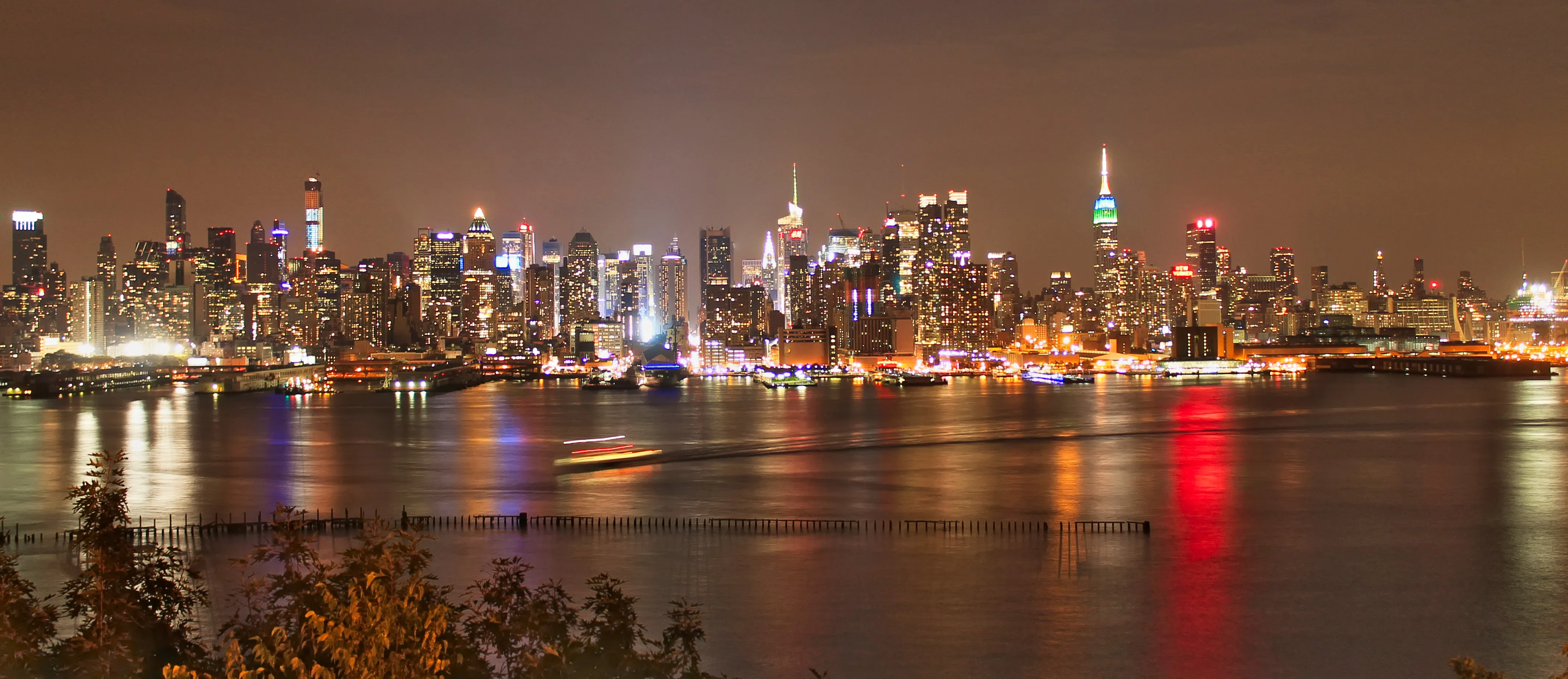 Manhattan skyline reflected across the Hudson at night